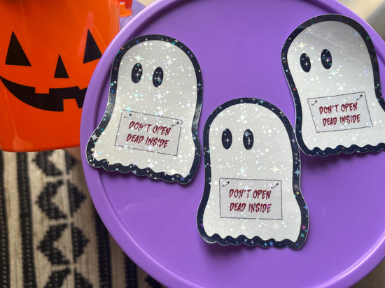 three holographic vinyl stickers of a ghost holding a sign that says, "don't open, dead inside" on a purple background
