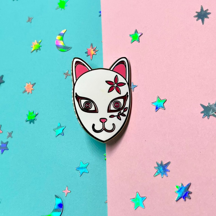 a kitsune fox mask with flowers and vine designs on a split color blue and pink background