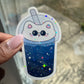 cat boba gleaming holographic sticker by a window with the sun shining
